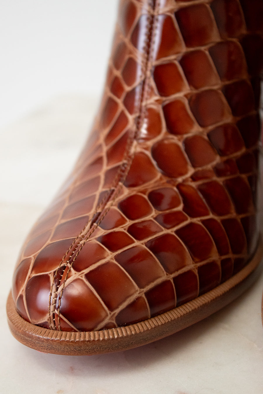 Close-up of a brown leather shoe with intricate pattern on a light background
