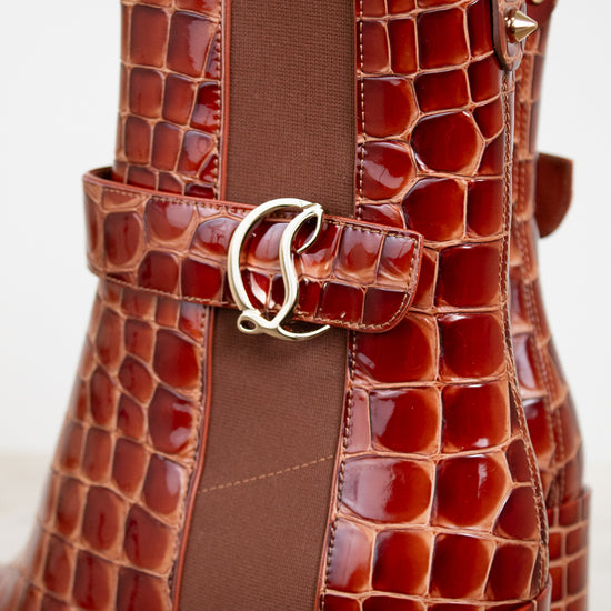 Brown crocodile-patterned handbag with a gold buckle on a white background