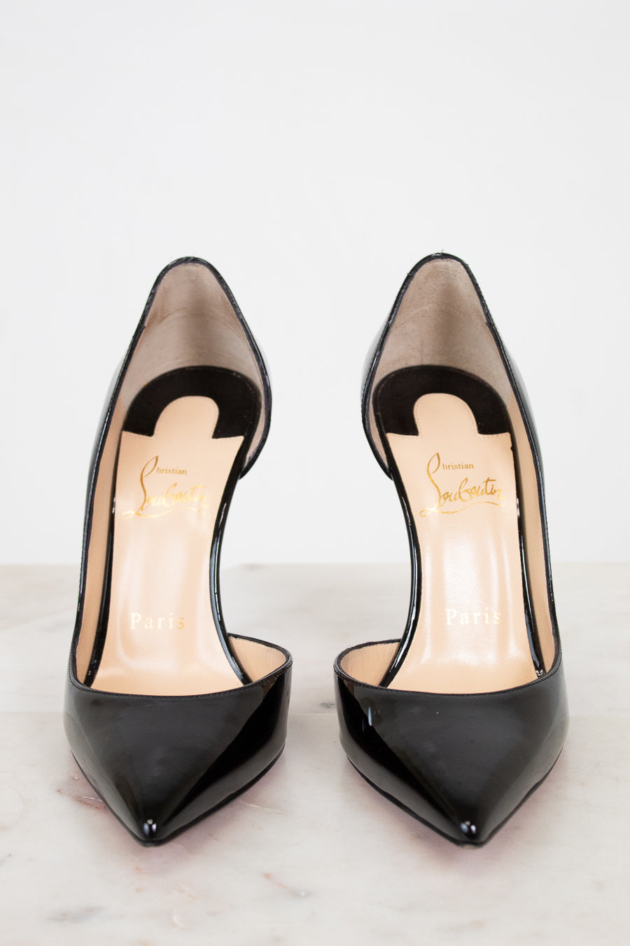 Black high-heeled shoes with a brand logo on a light background