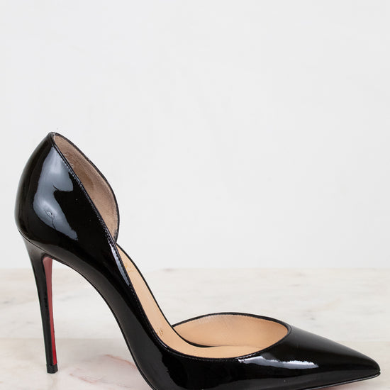 Black high-heeled shoe with a red sole on a light background