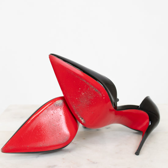 Red high-heeled shoes with black soles on a white surface