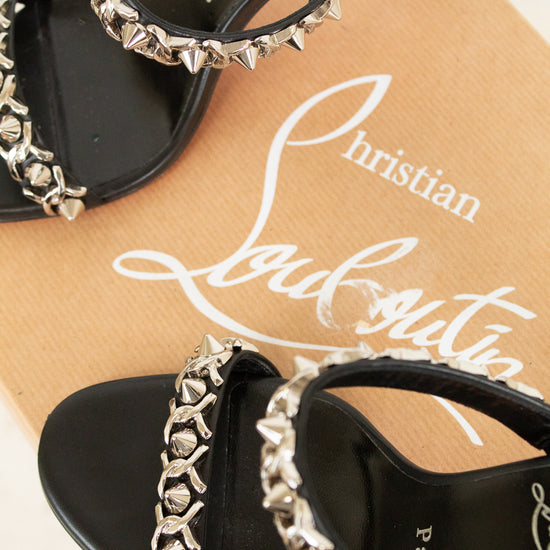 Black high-heeled sandals with silver studded details on a Christian Louboutin box.