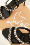 Black high-heeled sandals with silver studded details on a Christian Louboutin box.