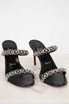 Black high-heeled sandals with chain detailing on a white background