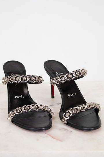 Black high-heeled sandals with chain detailing on a white background