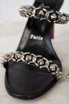 Black sandal with silver chain detail on a light background