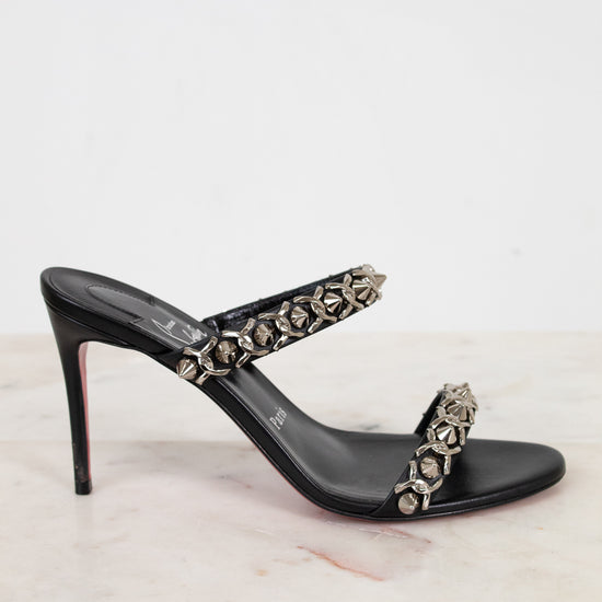 Black high-heeled sandal with embellishments on a light background