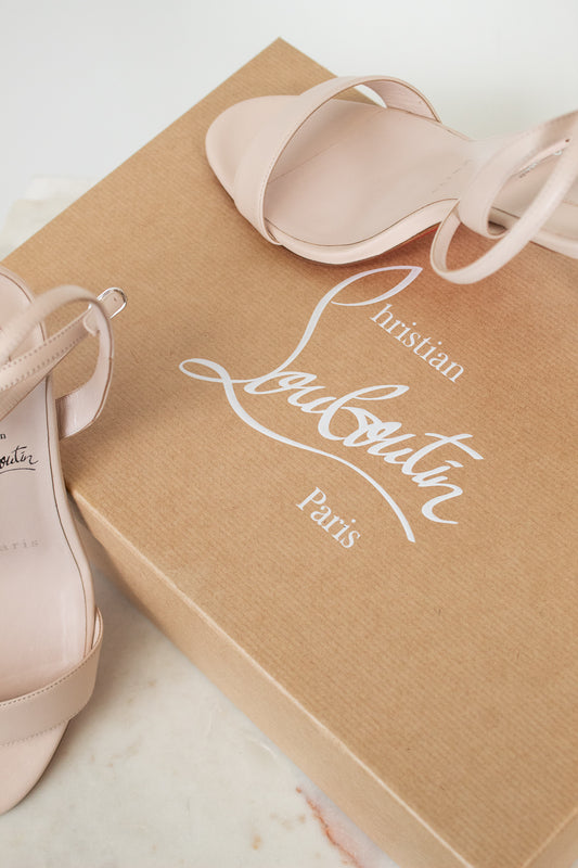 Pair of pink high-heeled shoes on a Christian Louboutin box.