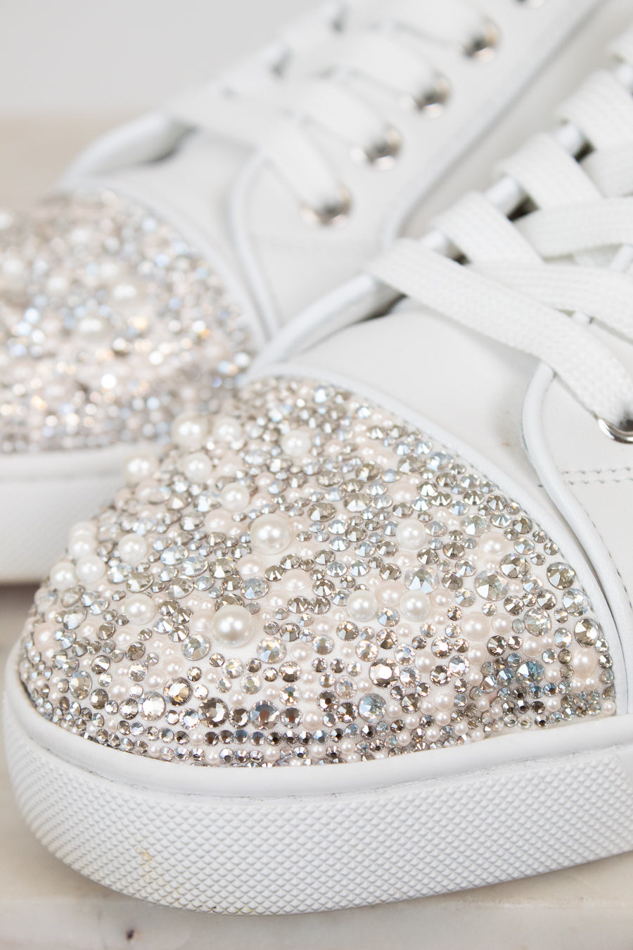 White sneakers with crystal and pearl embellishments on a light background