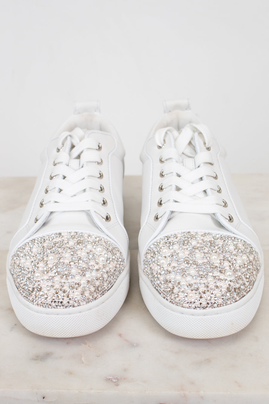 White sneakers with crystal and pearl accents on a light background