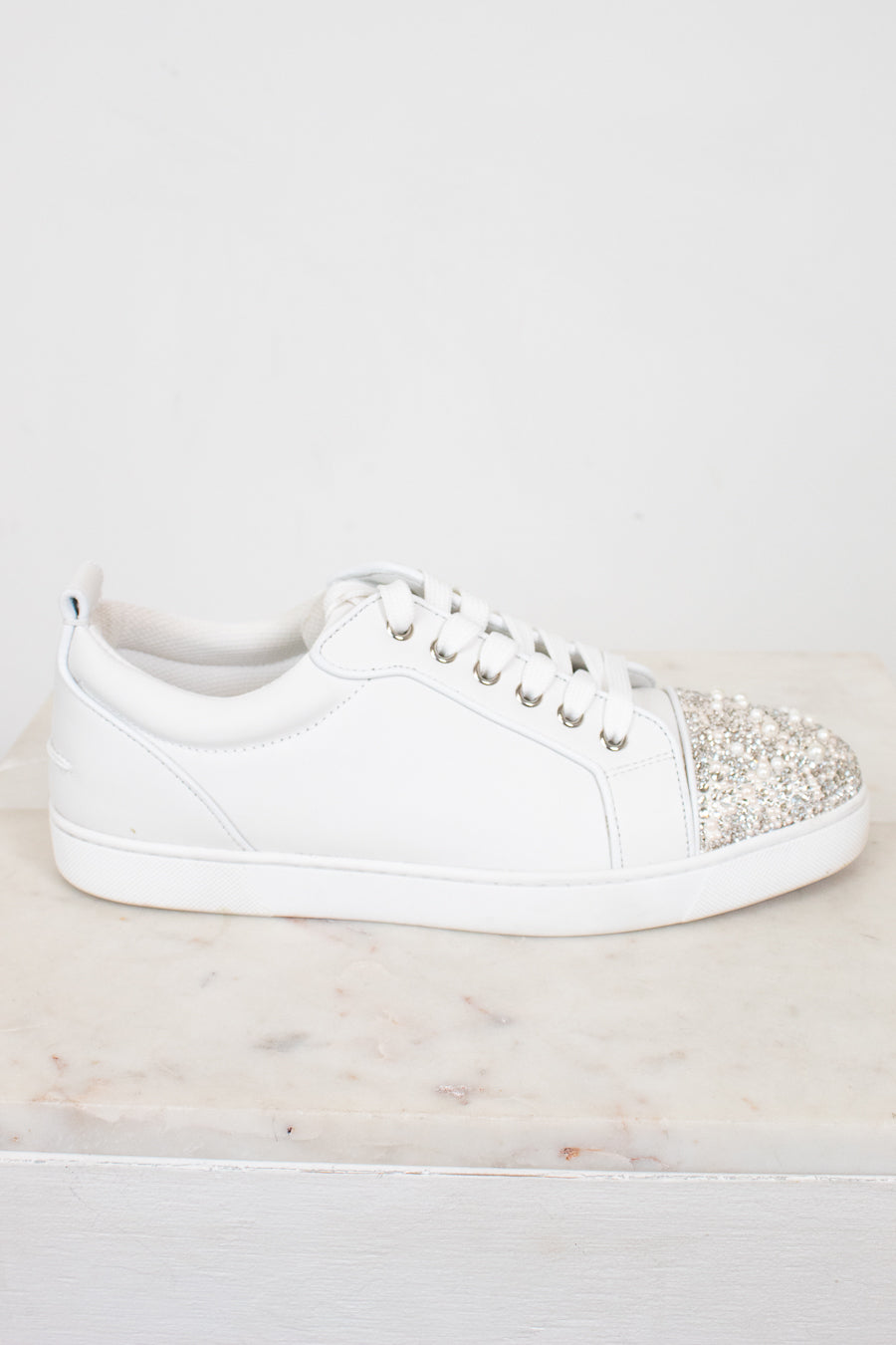 White sneaker with rhinestone embellishments on a light gray background
