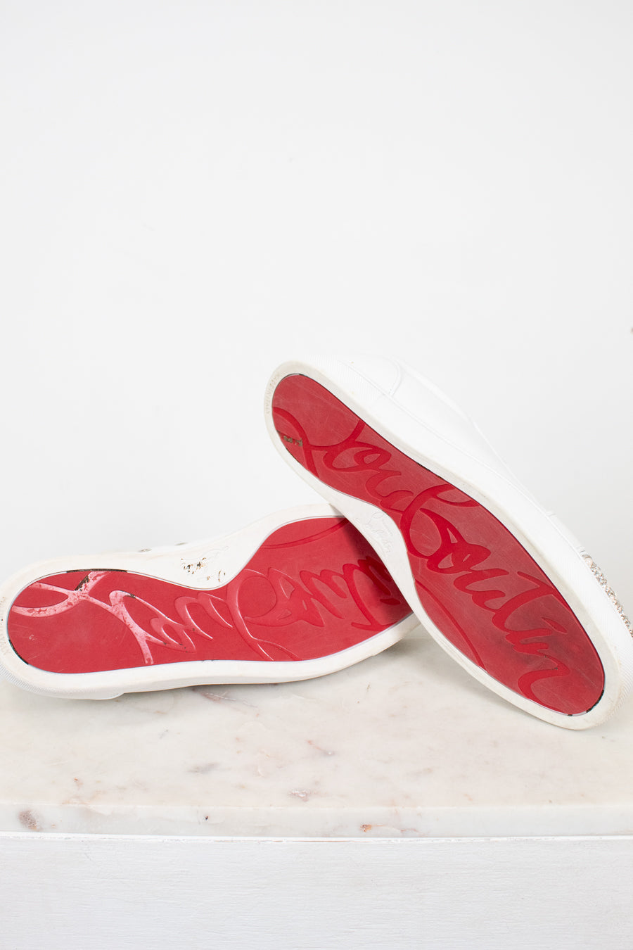 Red and white soles of sneakers on a marble surface