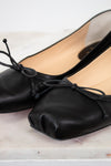 Black ballet flats with bow details on a light wooden surface