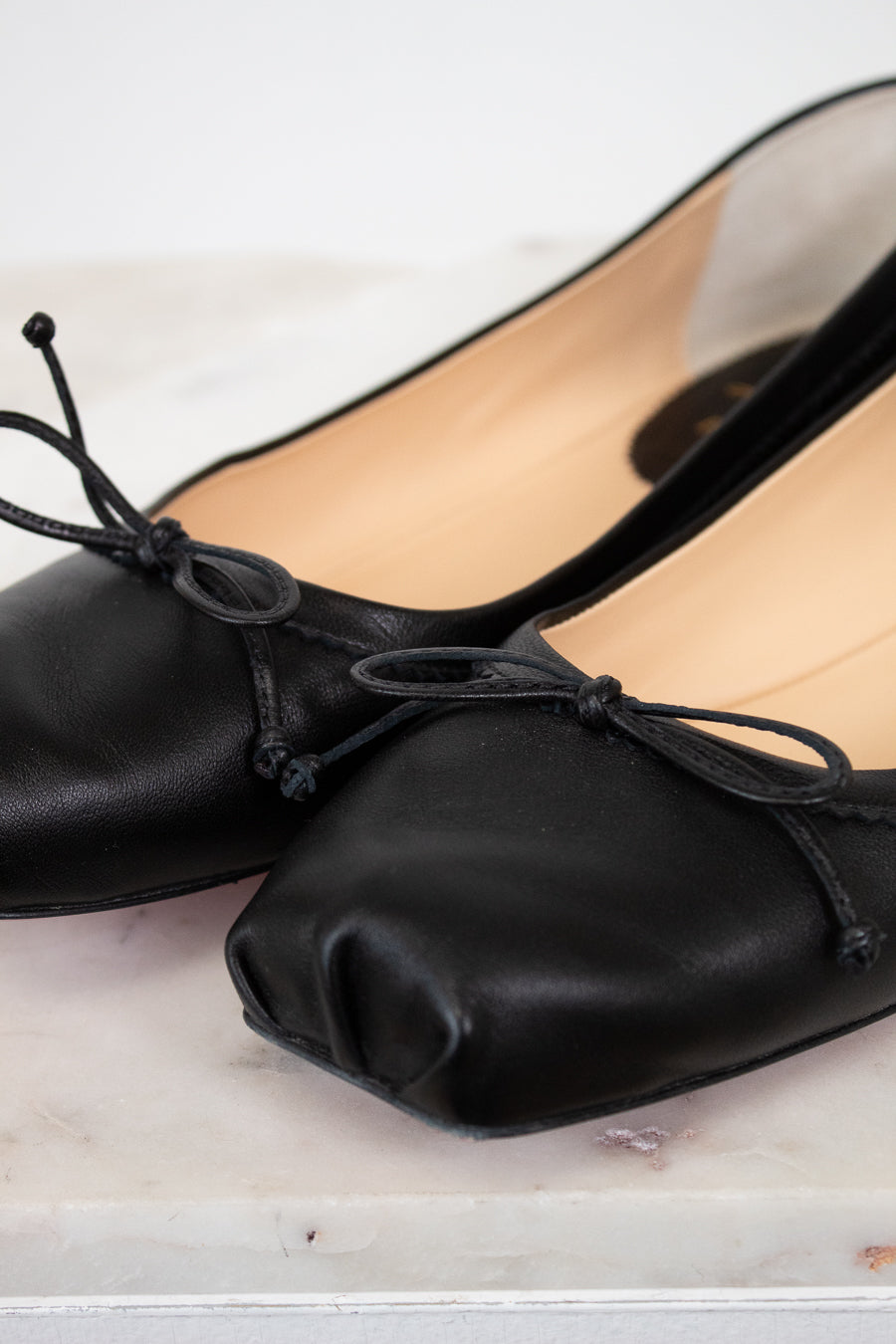 Black ballet flats with bow details on a light wooden surface