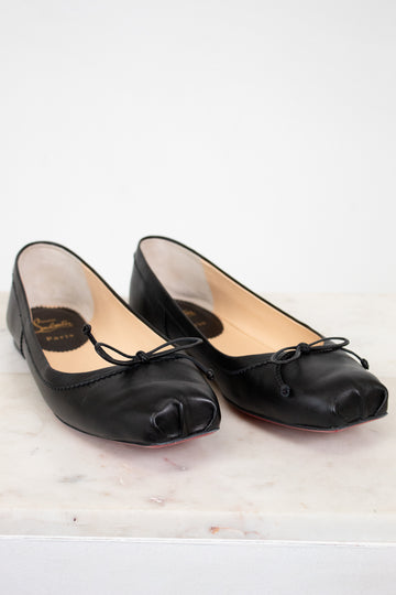 Pair of black leather shoes with bow details on a white surface