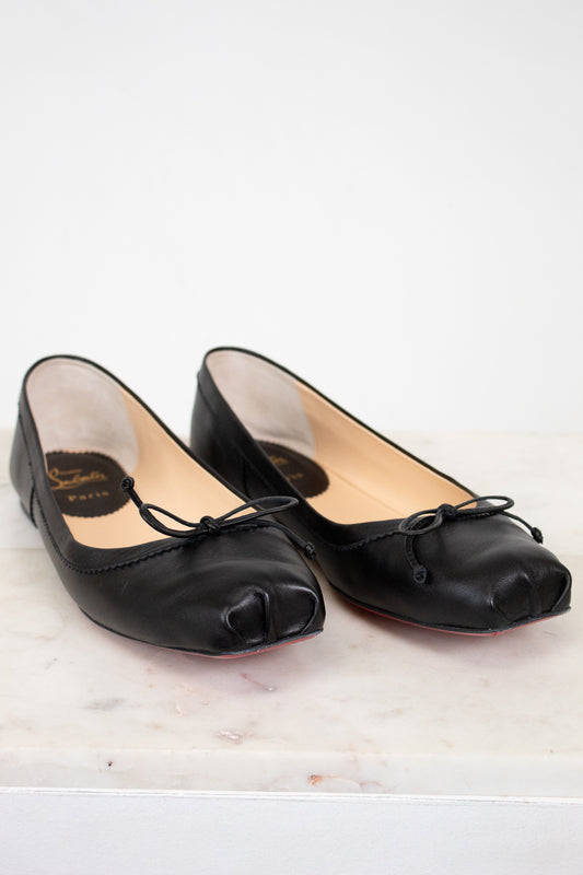 Pair of black leather shoes with bow details on a white surface