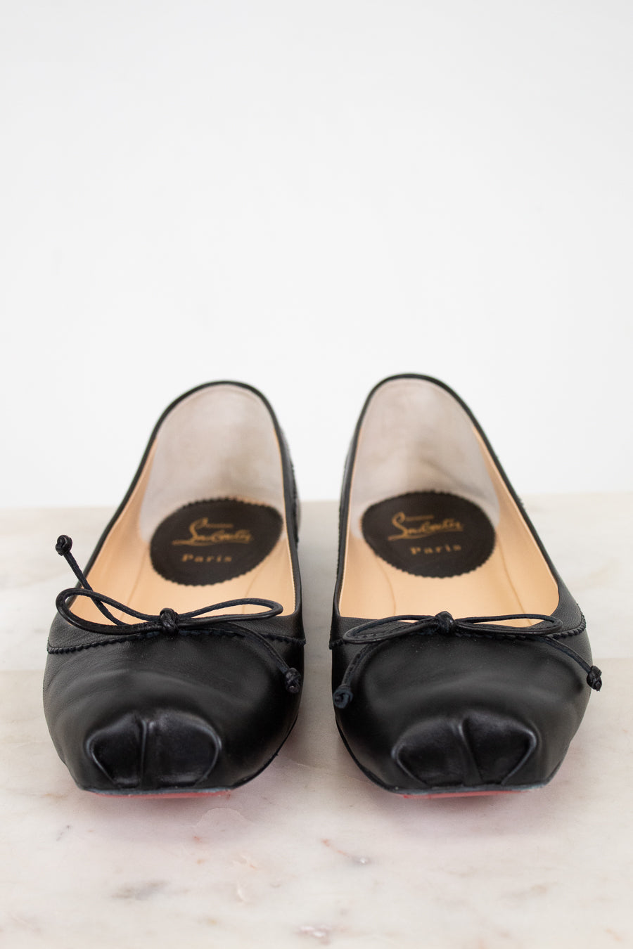 Pair of black high-heeled shoes with brand logo on a light background