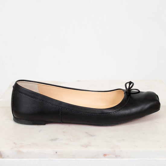 Black ballet flat shoe on a white marble surface