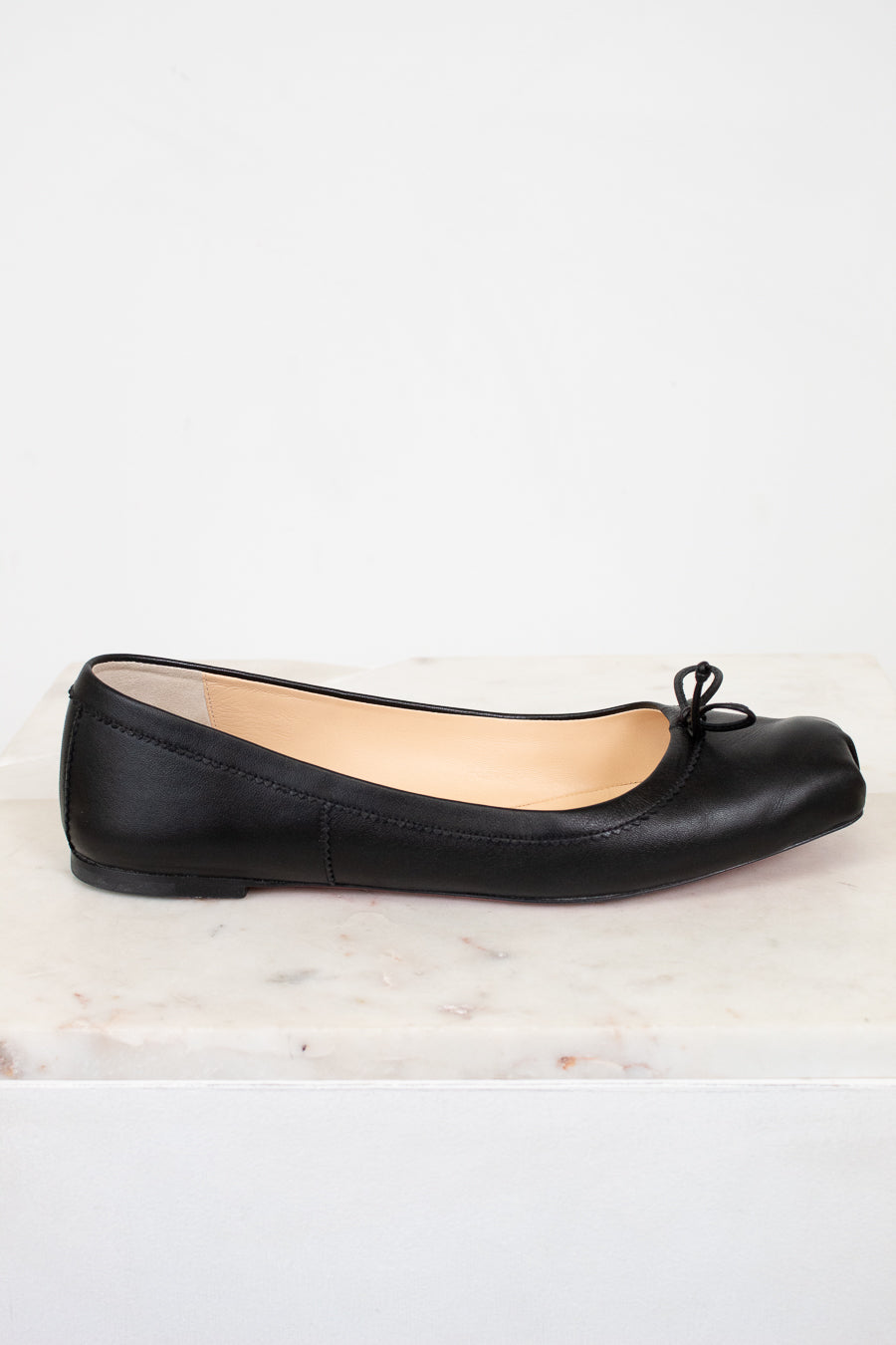 Black ballet flat shoe on a white marble surface