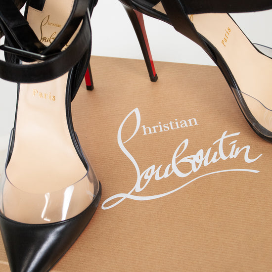 A pair of Christian Louboutin black leather high-heeled sandals with transparent PVC side panels and red soles, displayed on top of a brown shoebox with the white Christian Louboutin logo.