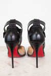 A pair of black leather high-heeled sandals with ankle straps, shown from the back on a light marble surface against a white background. They feature a signature red sole, characteristic of Christian Louboutin.