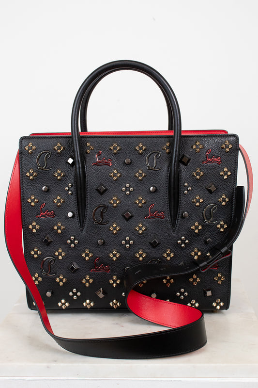 Black handbag with red accents and gold embellishments on a white background
