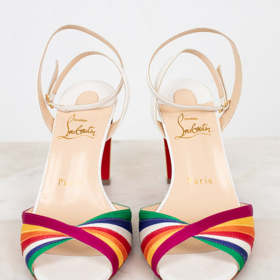 Pair of white heels with rainbow-striped detail with brand name on a light background