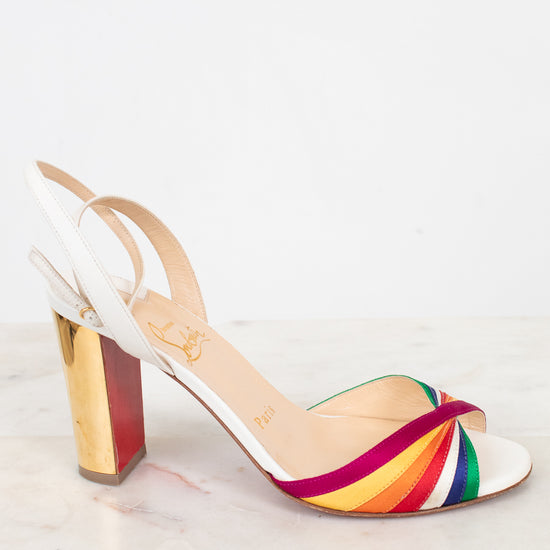 White sandal with a rainbow strap and gold chunky heel on a white background
