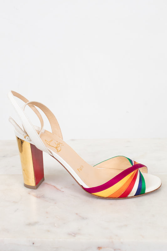 White sandal with a rainbow strap and gold chunky heel on a white background