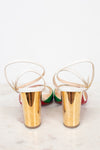 Gold chunky heel of shoes with white soles on a light background