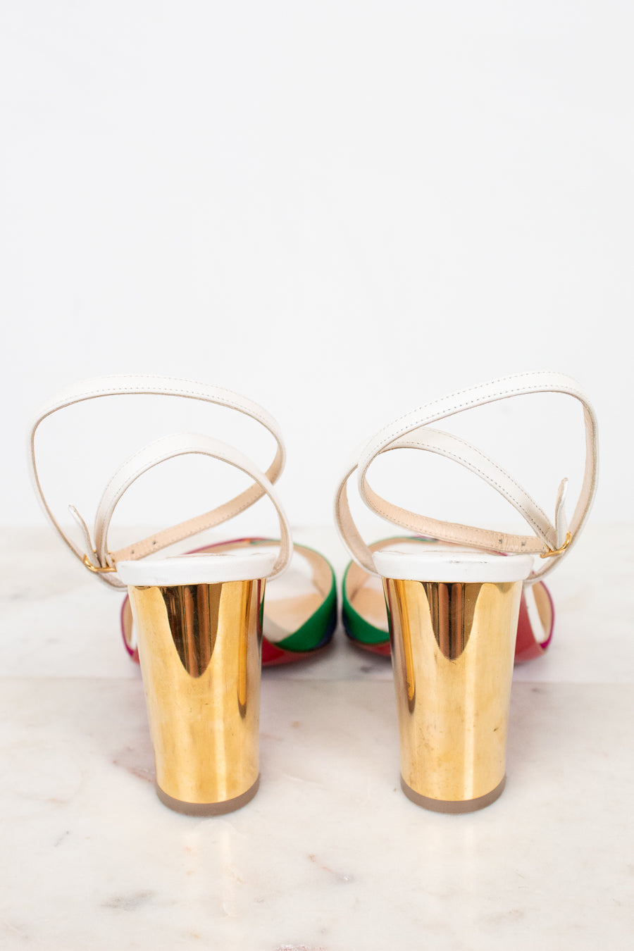 Gold chunky heel of shoes with white soles on a light background