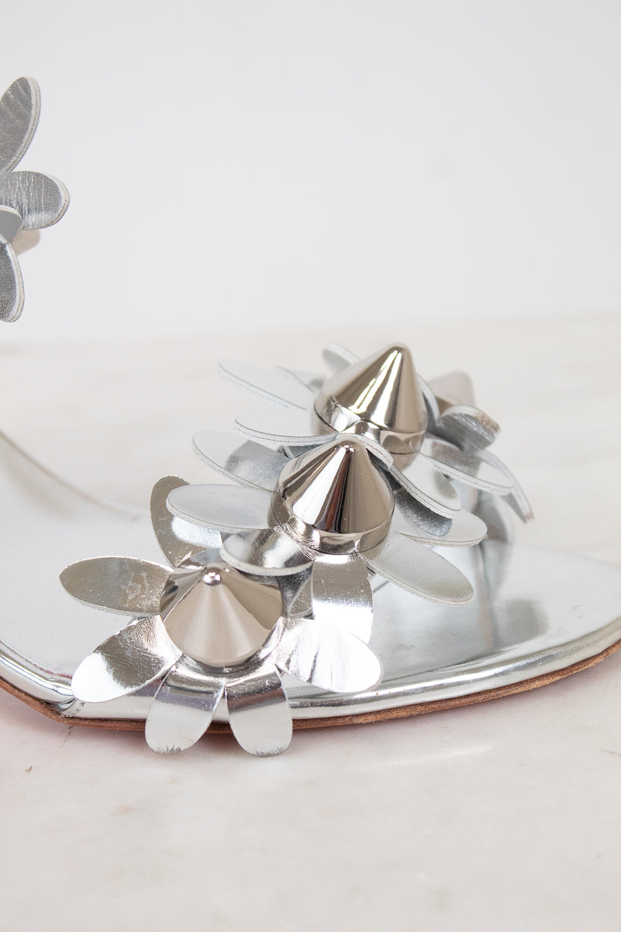 Close-up of silver studded floral shoe on a white background