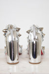 Pair of silver high-heeled shoes with studded details on a white background