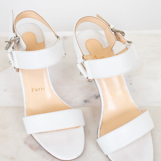 White high-heeled sandals with a brand name on a light background