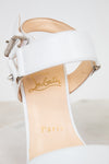 White high-heeled shoe with beige insole and 'Louboutin Paris' branding on a light gray background