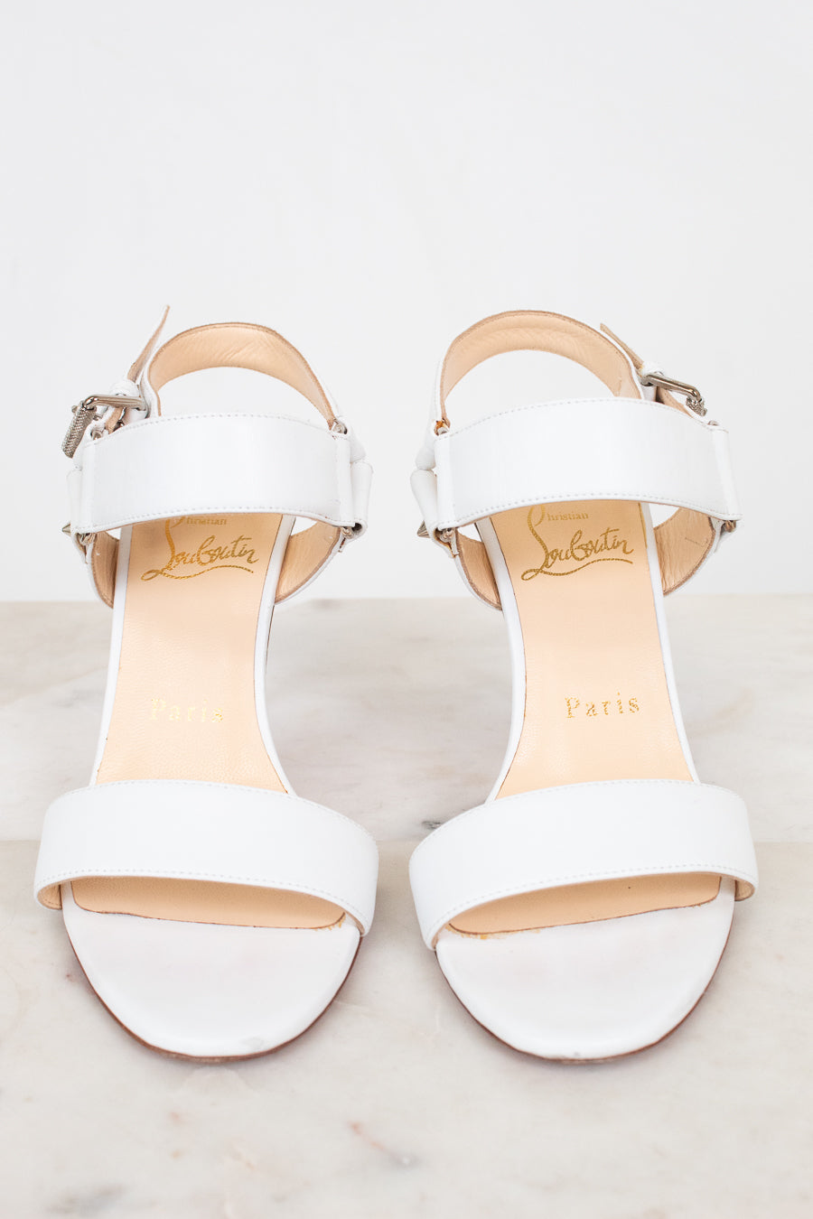 White high-heeled sandals on a light background