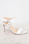 White high-heeled sandal with a red sole on a light gray background