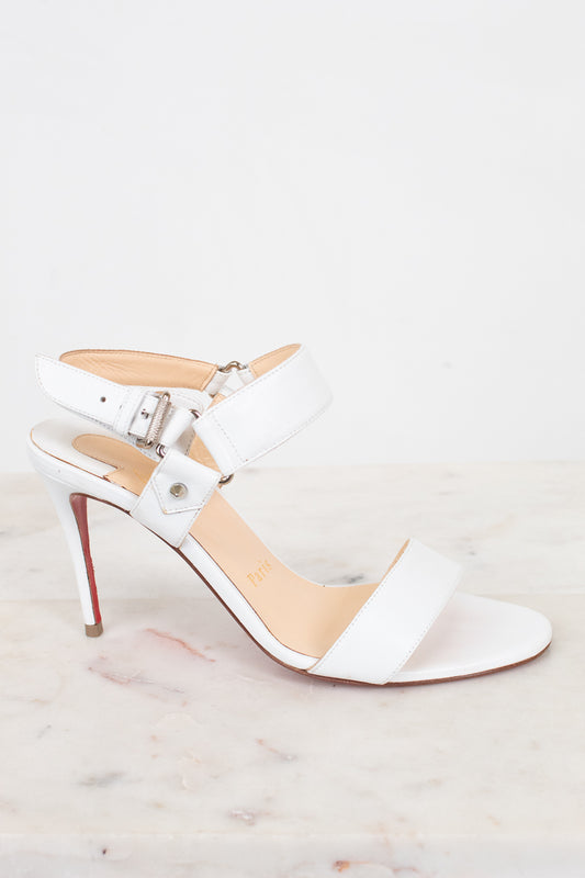White high-heeled sandal with a red sole on a light gray background
