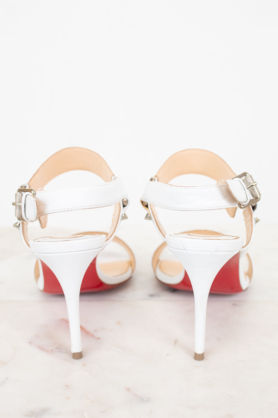 White high-heeled shoes with red bottom soles on a white background