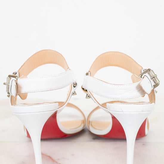 White high-heeled shoes with red bottom soles on a light background