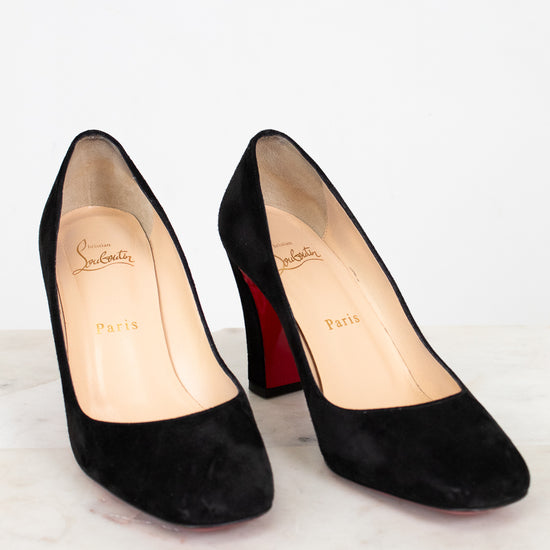 Black high-heeled shoes with red soles on a white background