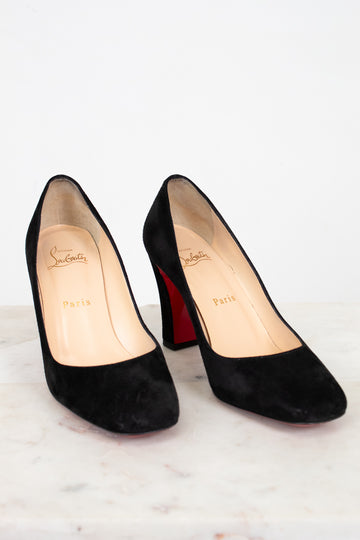 Black high-heeled shoes with red soles on a white background