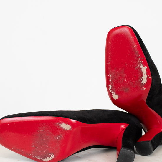 Red high-heeled shoes with black soles on a light marble surface.