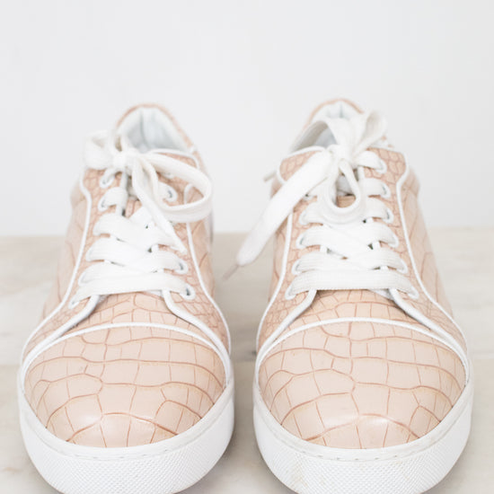 Pair of crocodile print beige sneakers with white soles on a light background