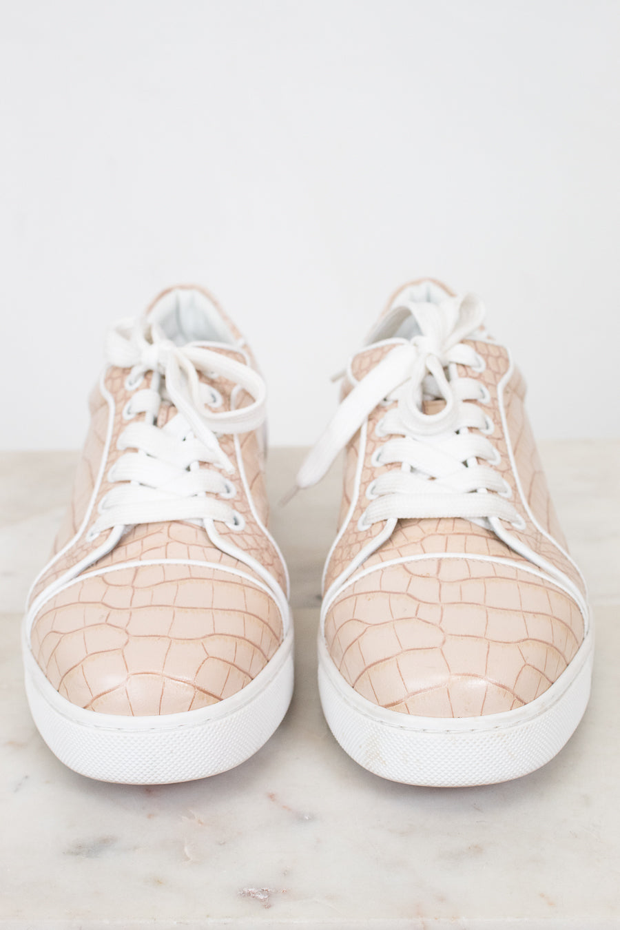 Pair of crocodile print beige sneakers with white soles on a light background