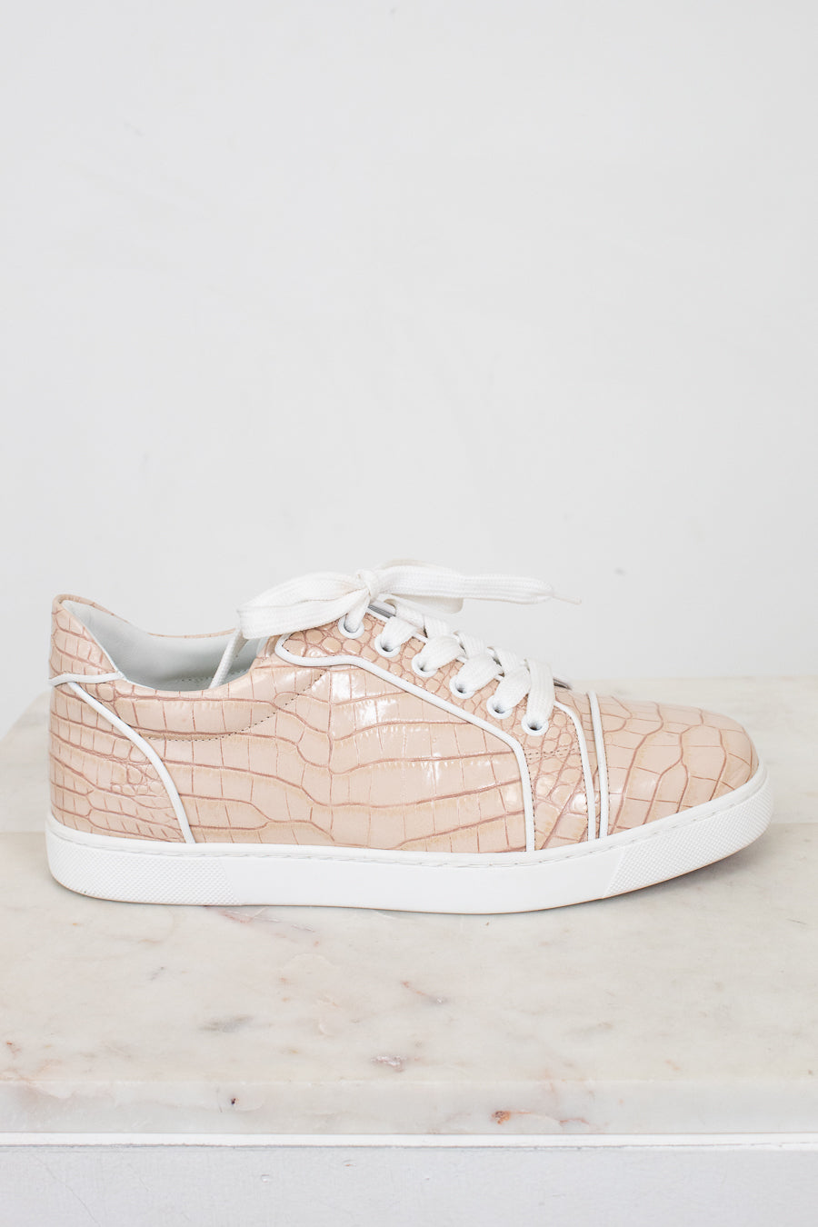 Beige sneaker with white sole on a light marble surface