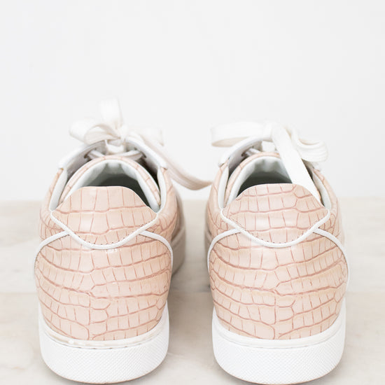 Pair of light pink crocodile-patterned sneakers on a white background