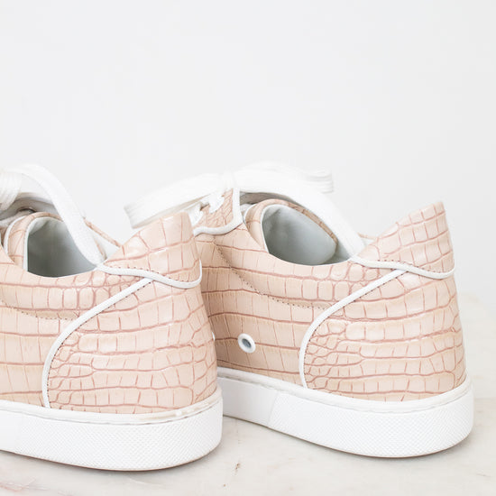 Pair of light pink sneakers with white soles on a light background