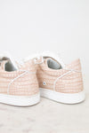Pair of light pink sneakers with white soles on a light background