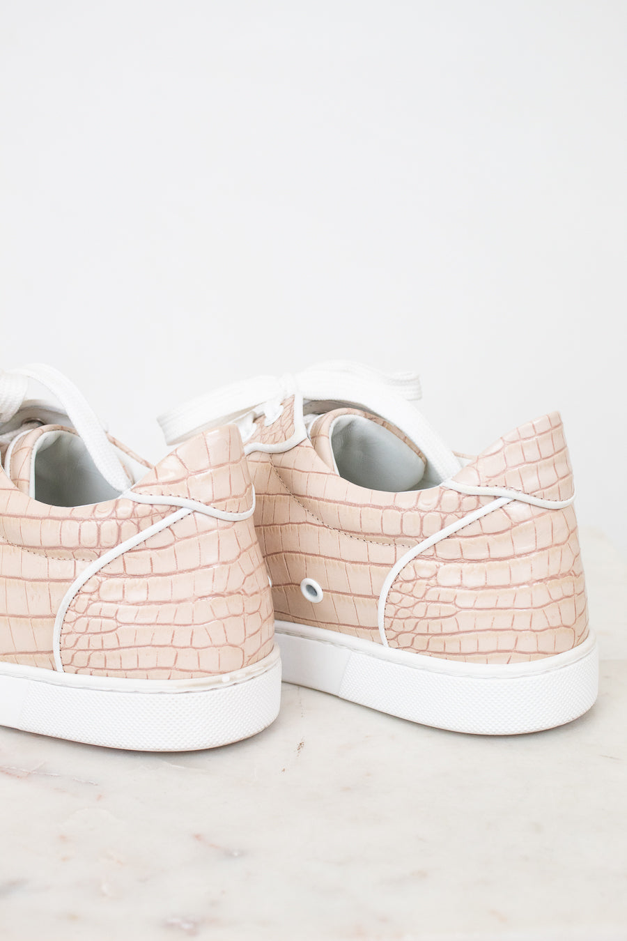 Pair of light pink sneakers with white soles on a light background